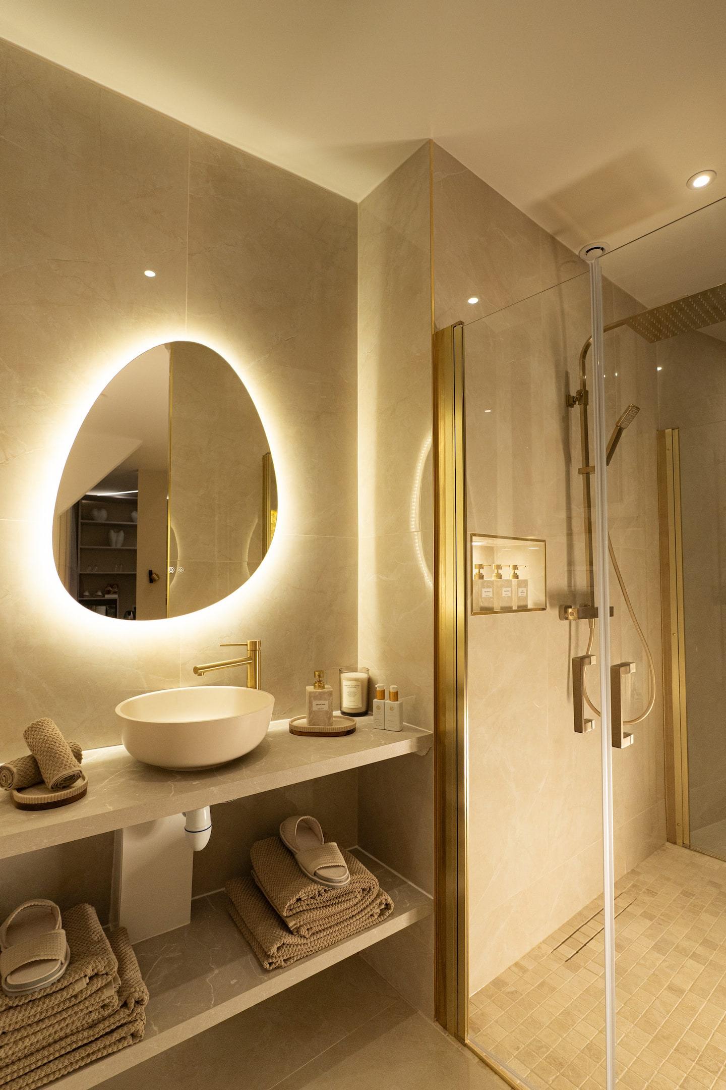 The bathroom with its backlit organic mirror and walk-in shower