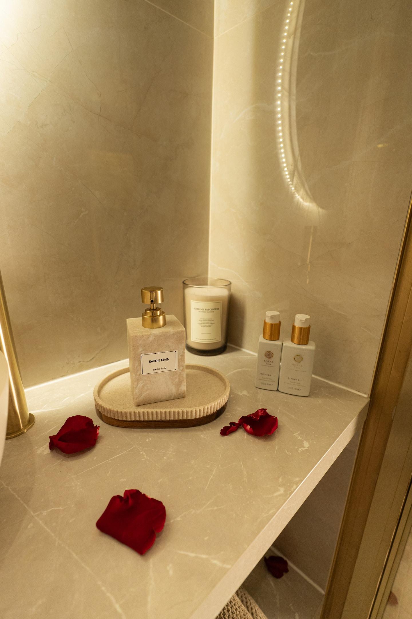 Candle, fragrances and rose petals on the marble tray